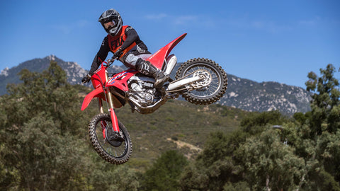 Motocross rider mid air whipping his red honda. There is no kick stand installed on the motorcycle so it's as light as possible for maneuvering around the track.