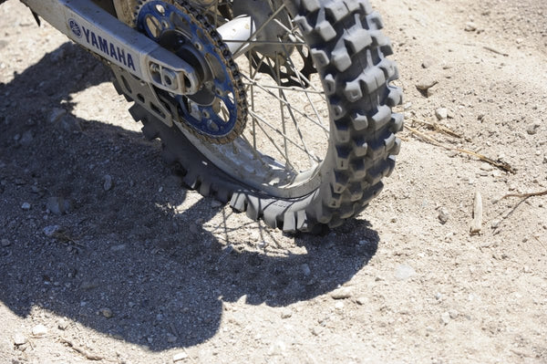 Pictured is a back tire that has a flat that was pictured in a moving still shot. You can see how the tire is excessively squating under the weight of the bike the side knobs that are in contact with the ground are splayed outward because the tire is no longer supported by the inside air pressure.