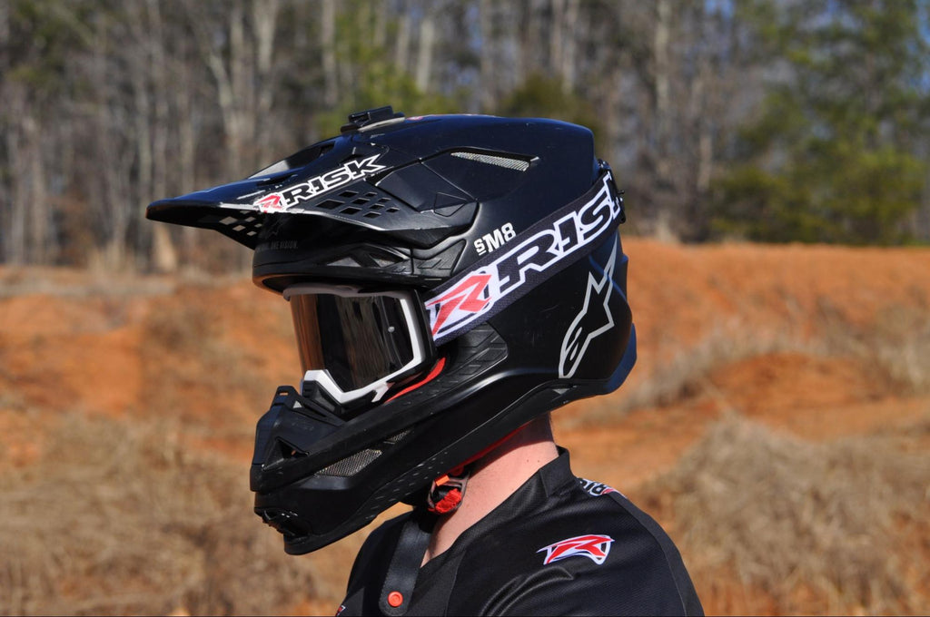 dirt biker wearing black helmet Goggles and jersey by Risk Racing hills tress in BG