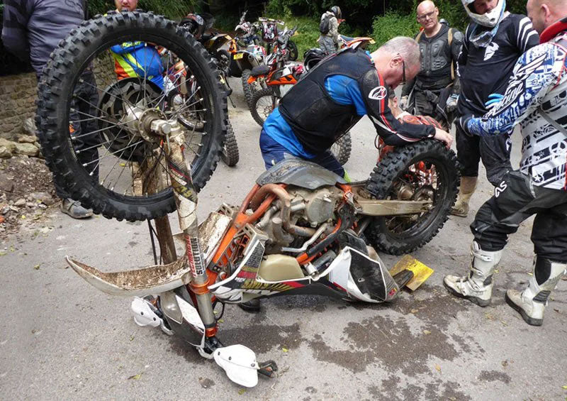 men gathered around an upside down dirt bike