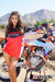 February Moto Model Alliyah wearing a Red & Black Risk Racing MX Jersey standing in front of a KTM dirt bike sitting on a Risk Racing ATS MX stand. At a MX track with mountains in background.