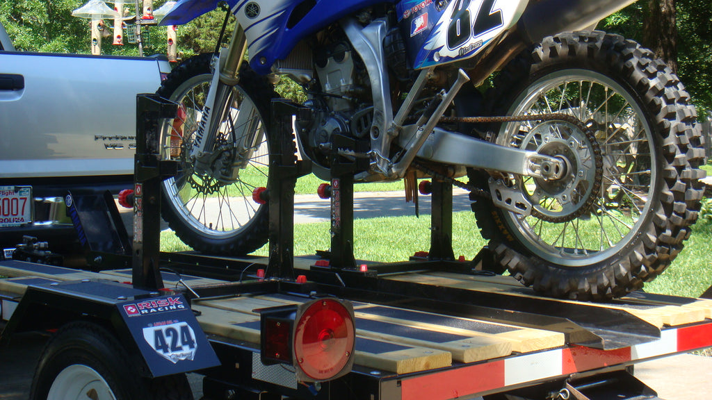 Bicicleta mx número 82 asegurada en un pequeño remolque de moto mediante un candado y carga de Risk Racing