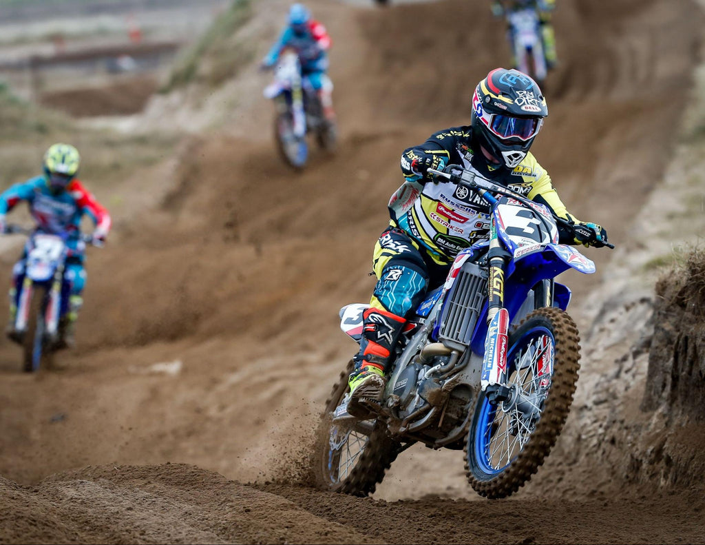 mx number 3 Risk Racing pro rider (in full Risk gear) exiting a rhythm section of a track w opponents in the background