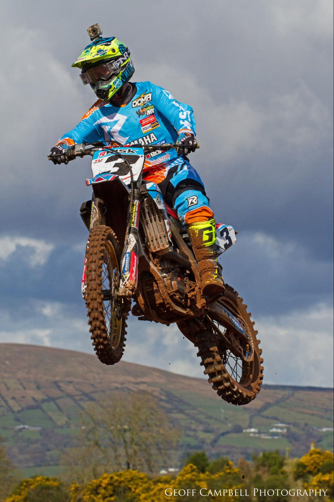 mx num 3 Risk Racing sponsored rider jumping through the air only sky and mountains in BG