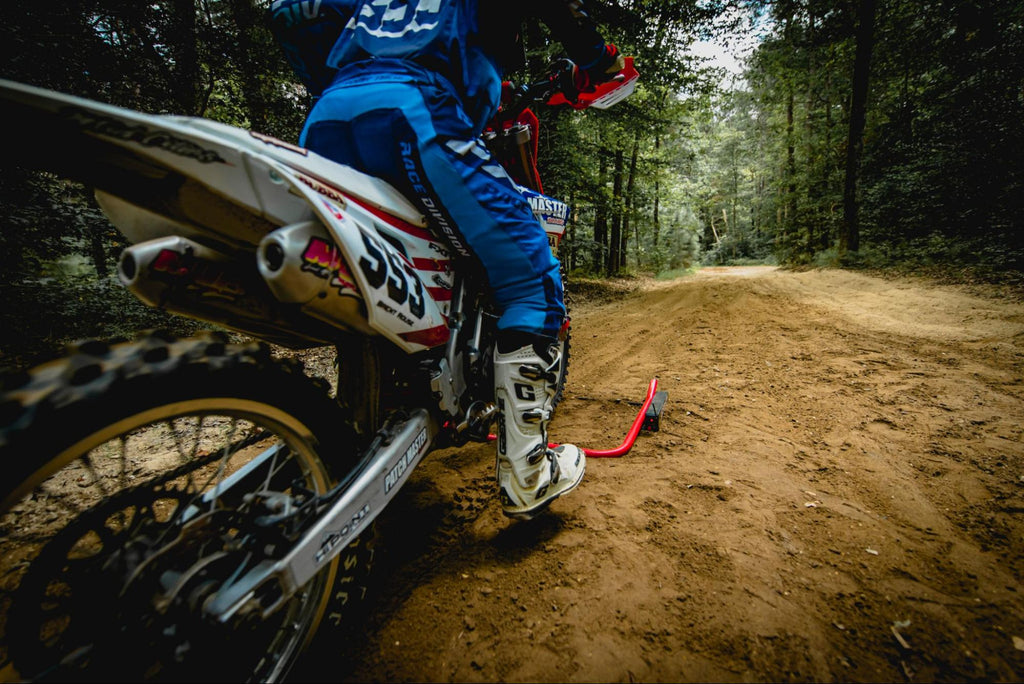 Motocross-Nummer 553 Üben Sie mit einem Rennstor mit einem Holshot-Rennstor mit Risk Racing auf einem Feldweg im Waldgebiet