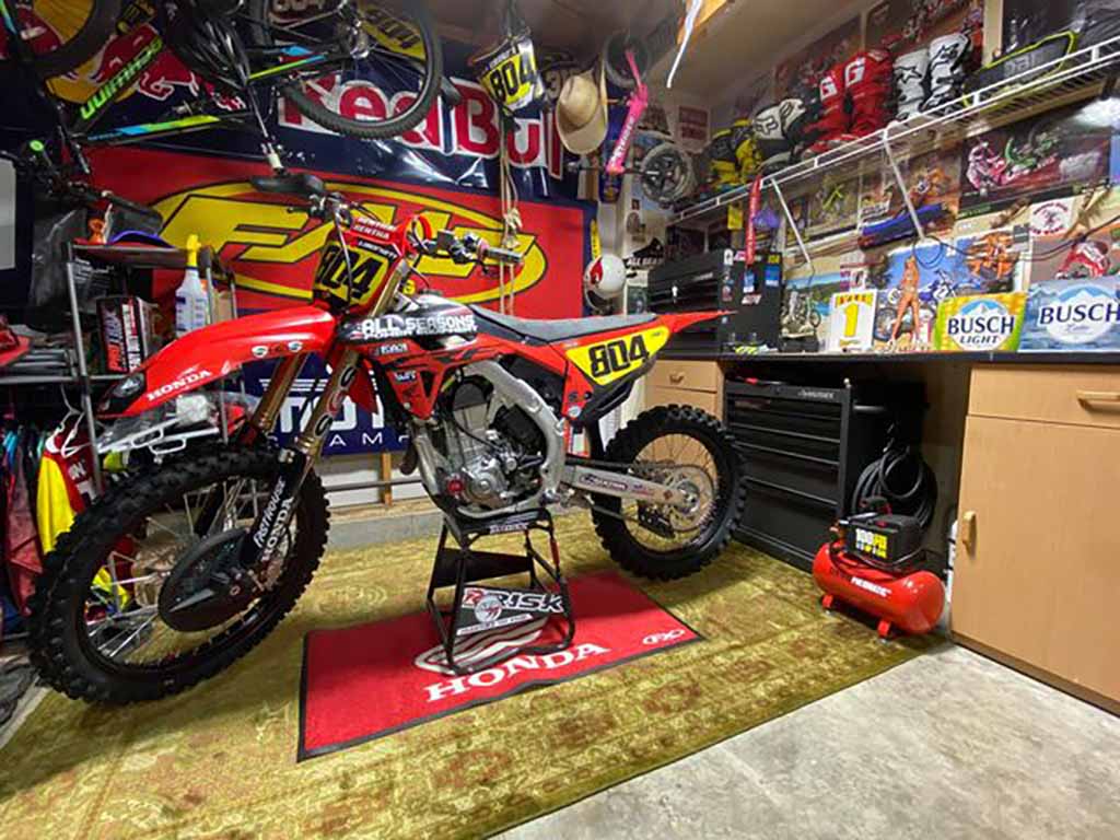 mx num 804 honda dirt bike rouge assis sur un stand ATS par Risk Racing dans un moto-garage