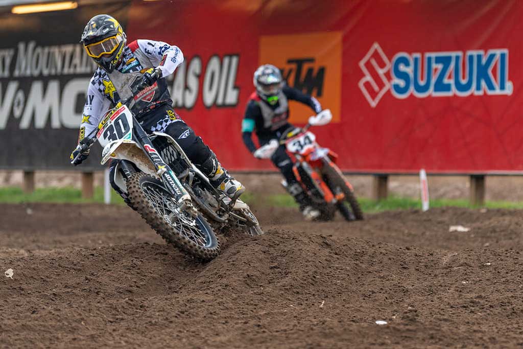 num 30 navigating a turn during a motocross race with num 34 close behind