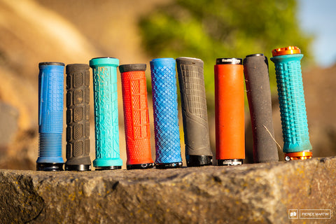 Various types of mountain bike grips lined up on a tree log.