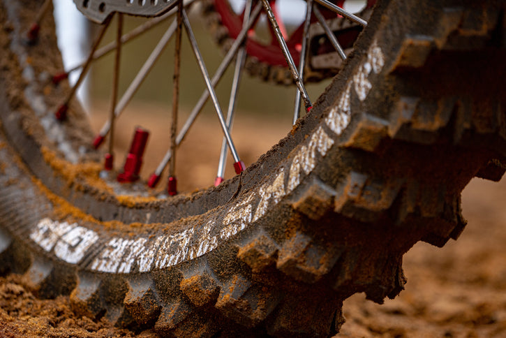 Super close up of a dirty motocross tire. Hawkstone GP writing upside down on the tire.