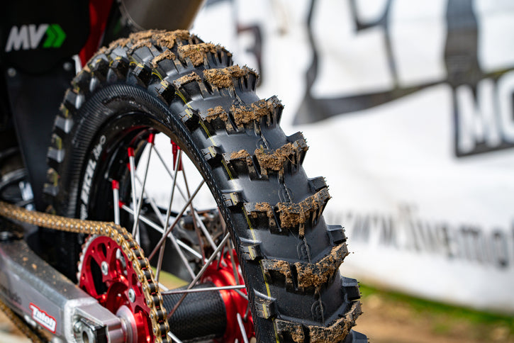 Close up of a Hawkstone paddle tire on a dirt bike with a little bit of mud on each paddle