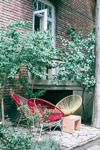 Acapulco chairs are placed in front of an urban townhome.