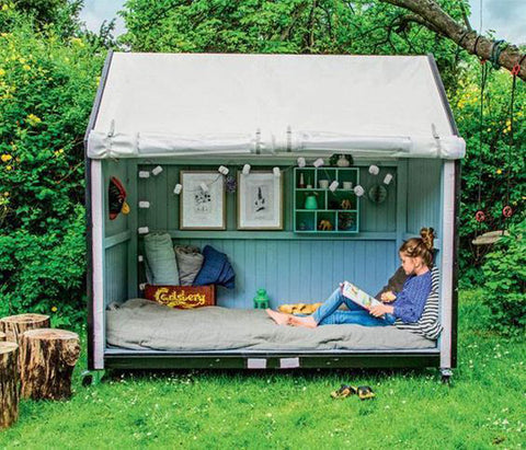 A child reads in a small garden shed converted into a reading nook.