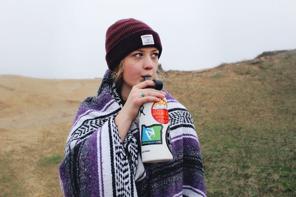 A woman drinking water from her bottle while hiking