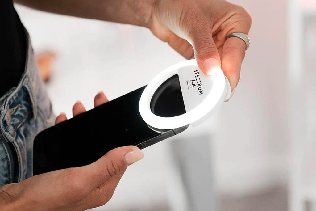 Close up of hands holding a phone with a ring light attached