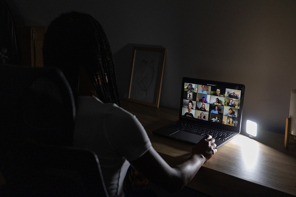 Woman sitting in a dark room while attending a conference call on her laptop