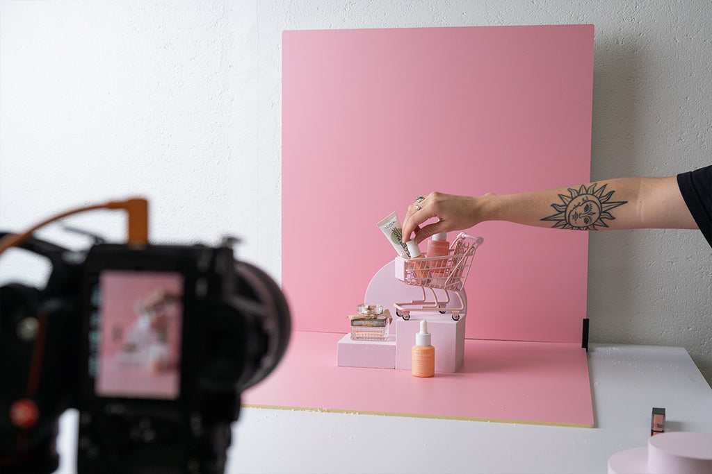 Photographer taking photos of a mini trolley positioned in front of a pink backdrop