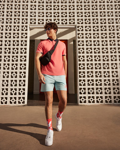 Model wearing a Psycho Bunny polo, short and cross-body bag