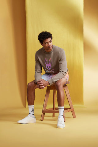 man sitting with a beige sweatshirt and a gradient swim