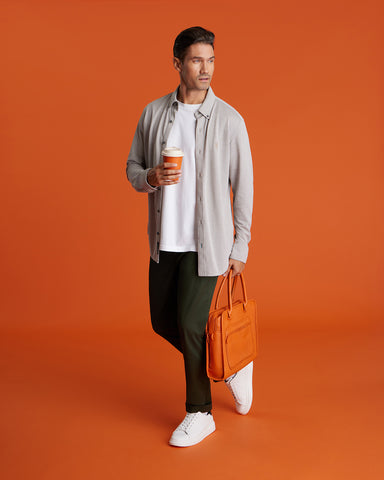 a man on an orange background with an open shirt, a white tee, a chino and sneakers