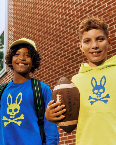 two kids wearing psycho bunny blue and yellow hoodie and sweatshirt and one with a football ball