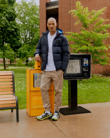 man aside a bench wearing psycho bunny's puffer jacket