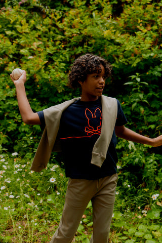 kid in the nature wearing psycho bunny throwing a ball