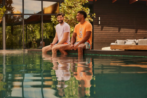 two guys with feets on the water next to a pool