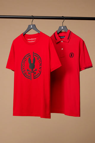 1 red tee shirt with a big design in the middle and a red polo hanging next to each other