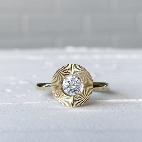A round white diamond in a 14k yellow gold Aurora ring