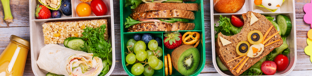 Assorted children's lunch boxes with lunch food items.