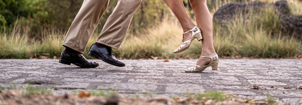 An outdoor dance floor with only the feet of two people dancing are shown.