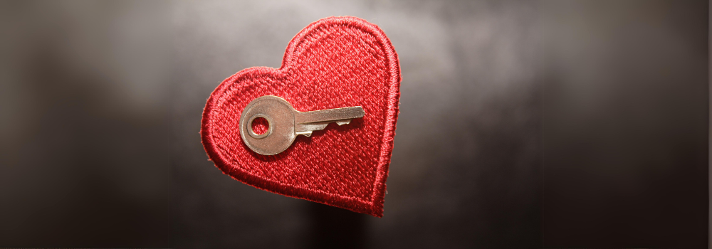 A cloth heart with a small key on top of it.