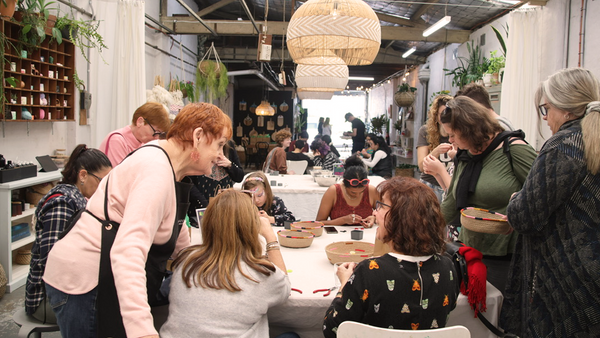 A group of happy people gathered around a craft activity in a converted warehouse space 