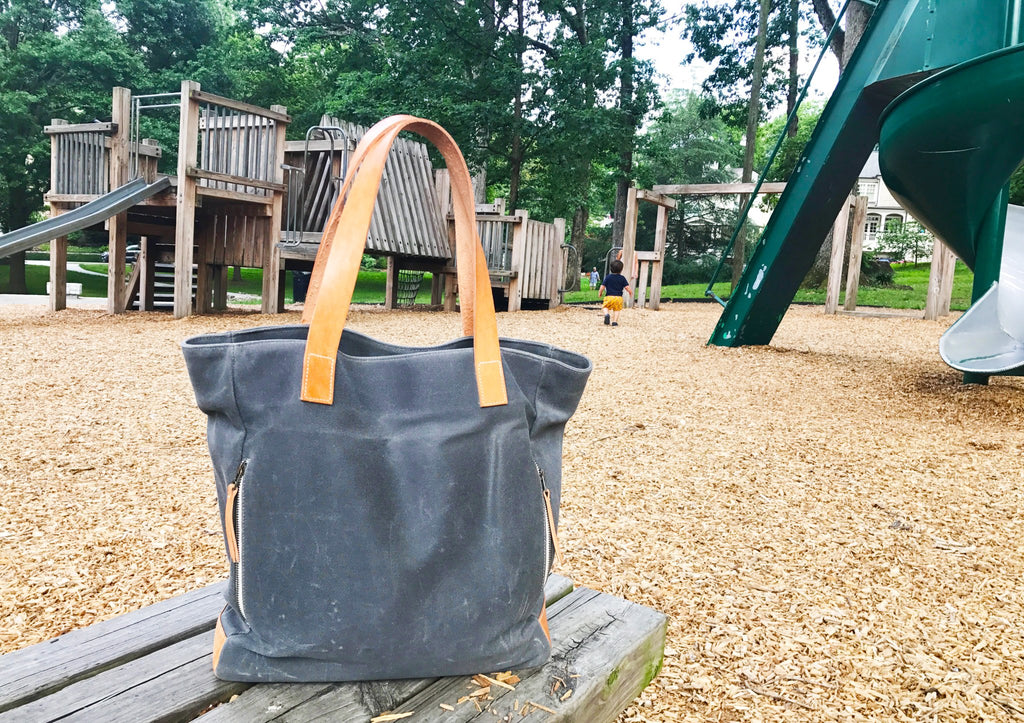 Notebooks and Honey carryall tote bag at the playground, the most versatile bag for moms. 