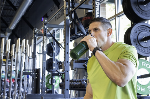 A man sitting in the gym sipping on Rewind Greens super greens