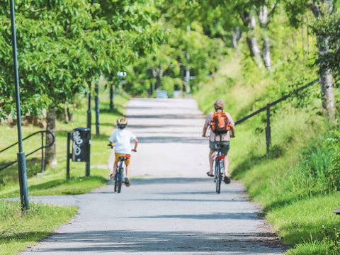 man and child on bikes cycling through park