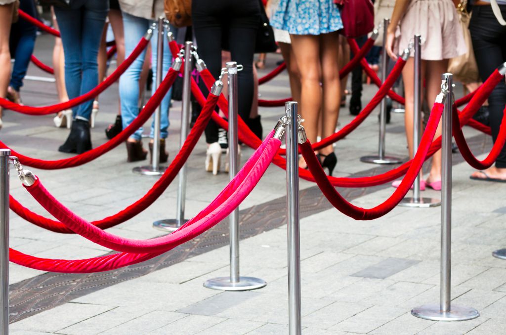 Red velvet rope stanchions organizing a crowd of people into lines
