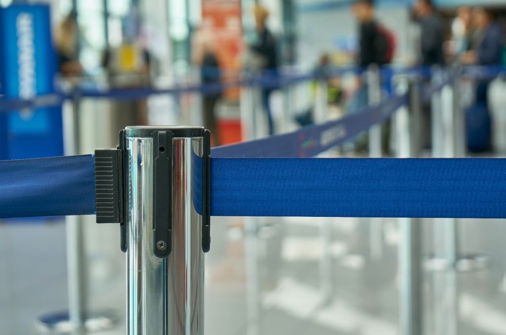 Close up shot of a silver retractable belt barrier stanchion with a blue belt.