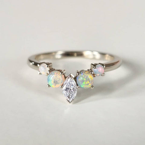 A close-up of an elegant Ring with Opal stone, placed on a white surface.