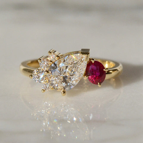 A close-up of a Diamond and Ruby Ring placed on a white surface.