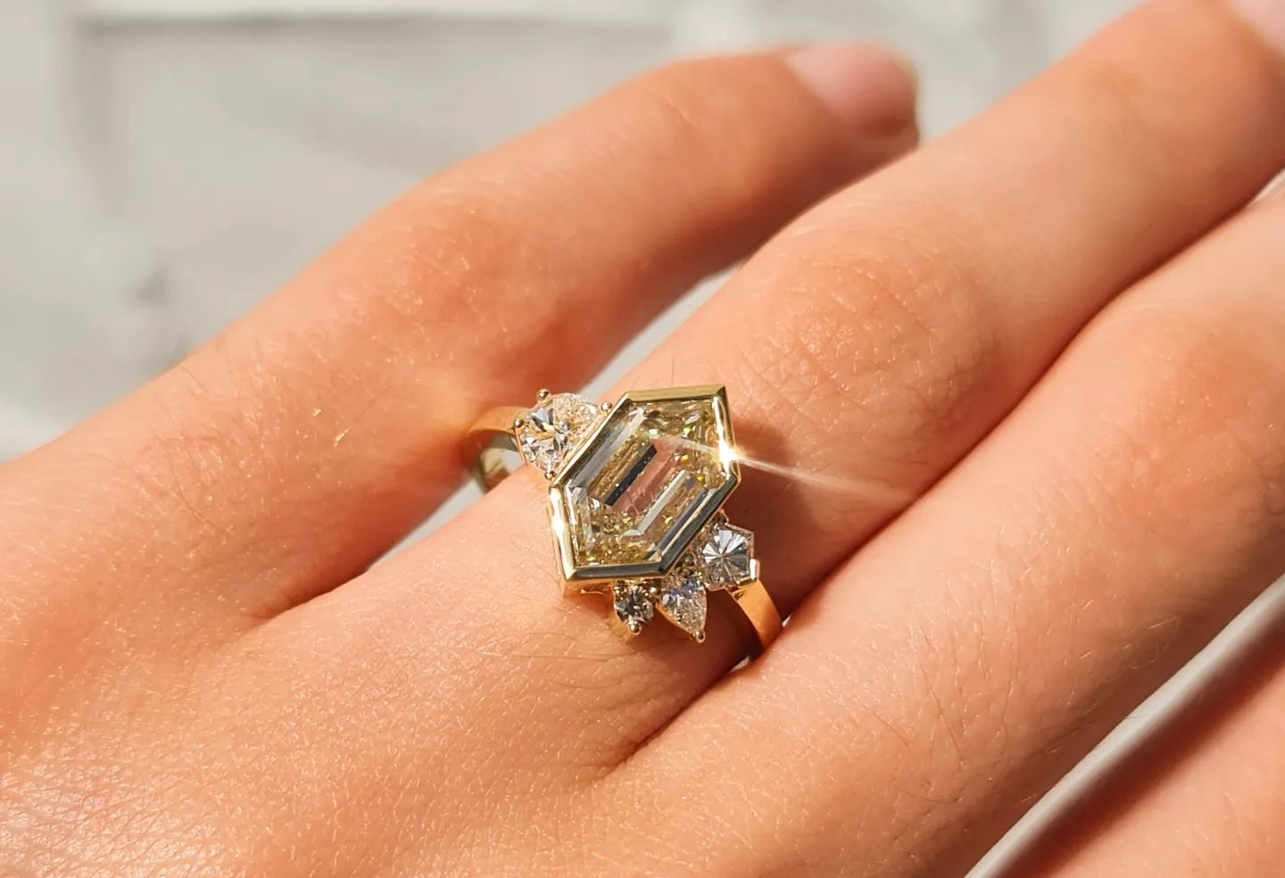 A close up of an asymmetrical engagement ring designed by Layla Kaisi Collection featuring a hexagonal yellow diamond centre stone with asymmetrical side stones