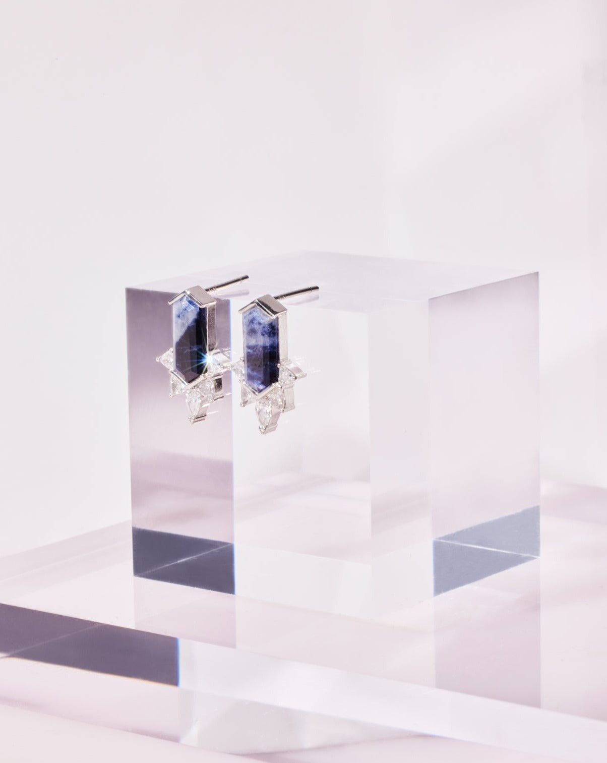 A stunning hexagonal cut Sapphire Diamond Earring placed on a white shinny surface.