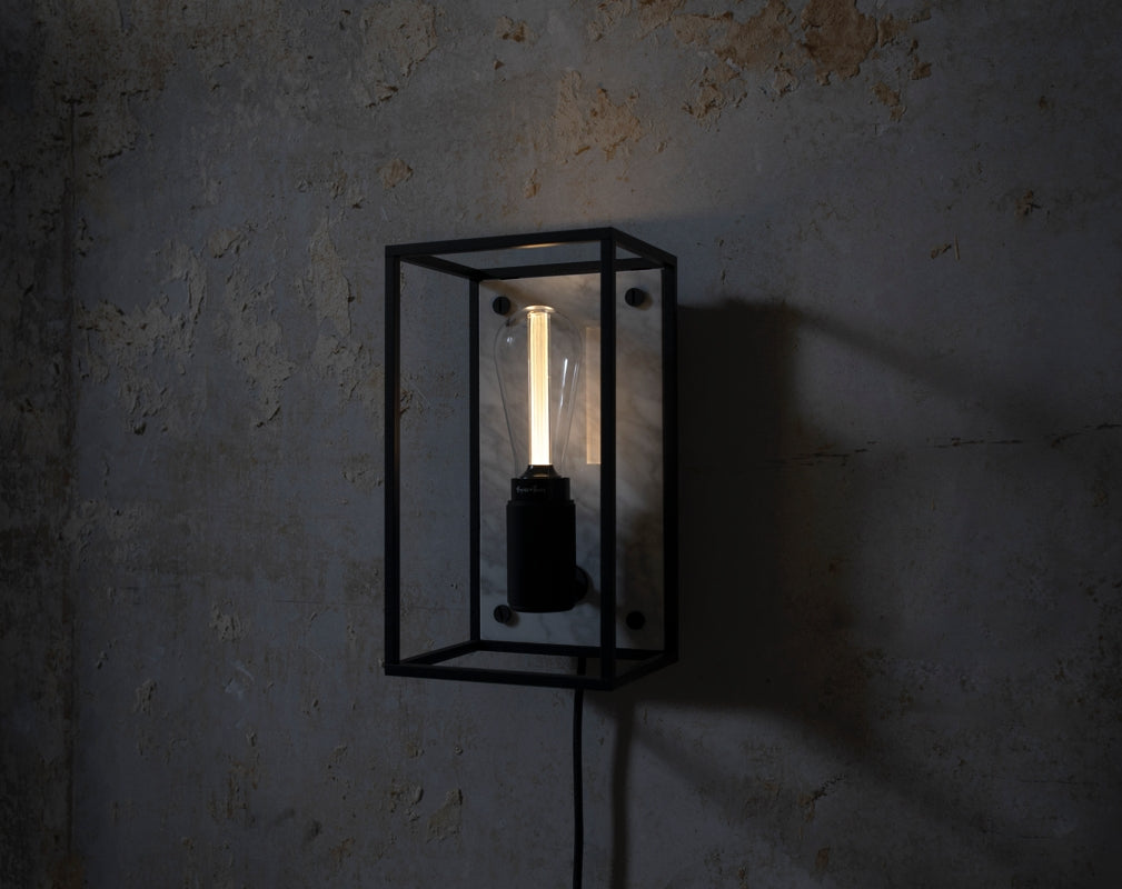 A Buster + Punch CAGED wall light illuminates an industrial backdrop