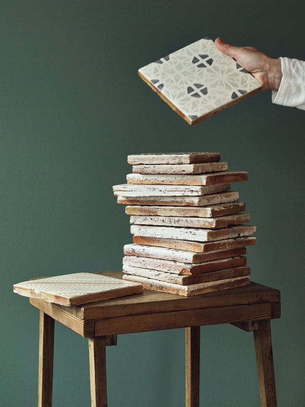 An arrangement of Claybrook tile designs stacked on a wooden stool