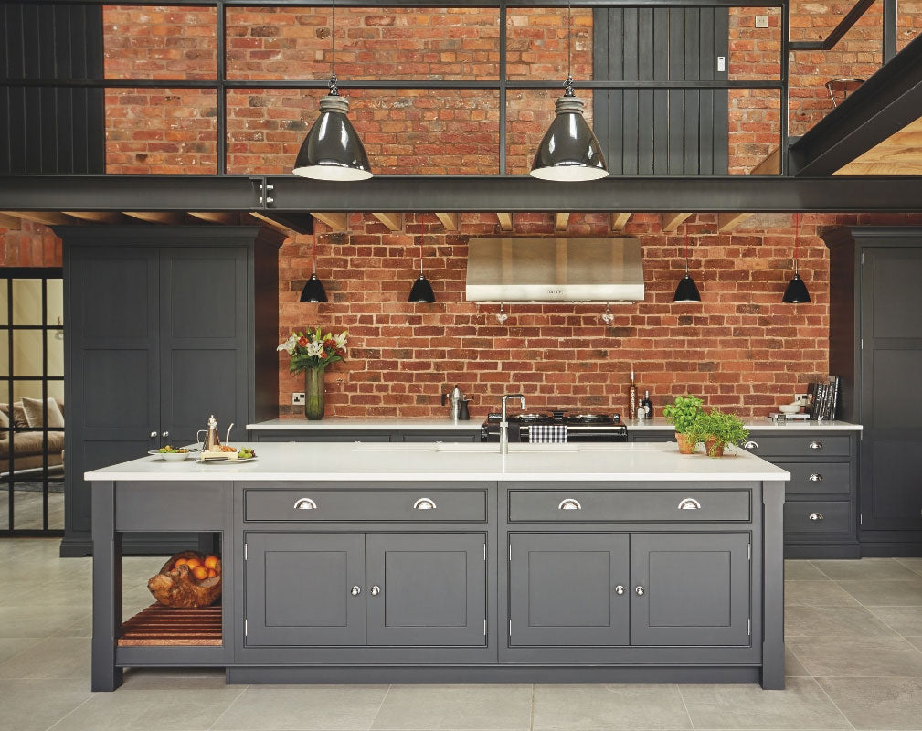 Industrial style shaker kitchen painted in charcoal grey against an exposed brick wall and featuring lots of original features. Kitchen by Tom Howley