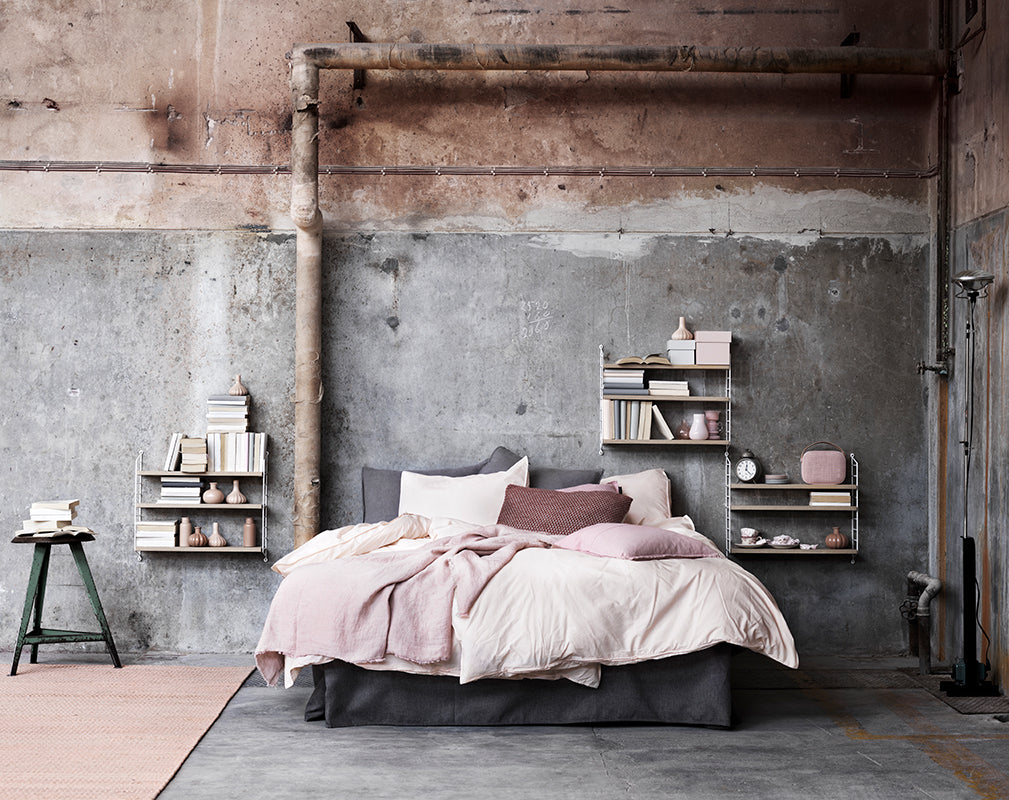 pastel industrial bedroom scheme with exposed pipework and wall mounted string shelving.