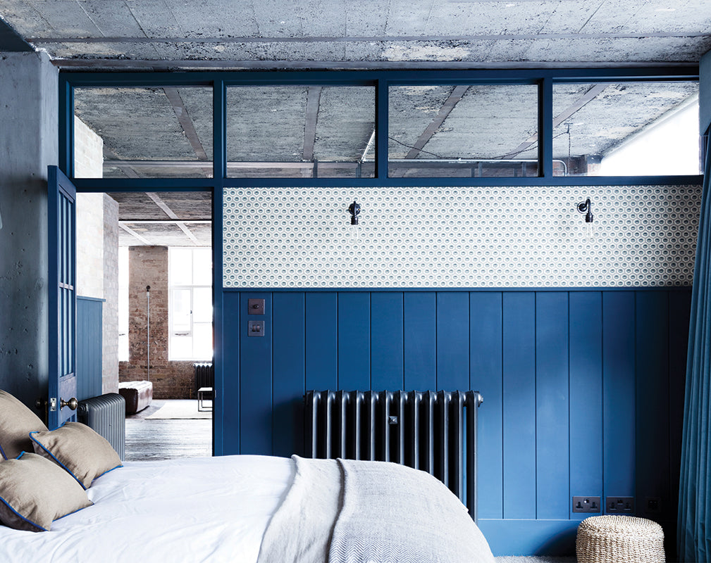 bedroom in a london warehouse conversion with exposed brick and raw concrete ceiling.