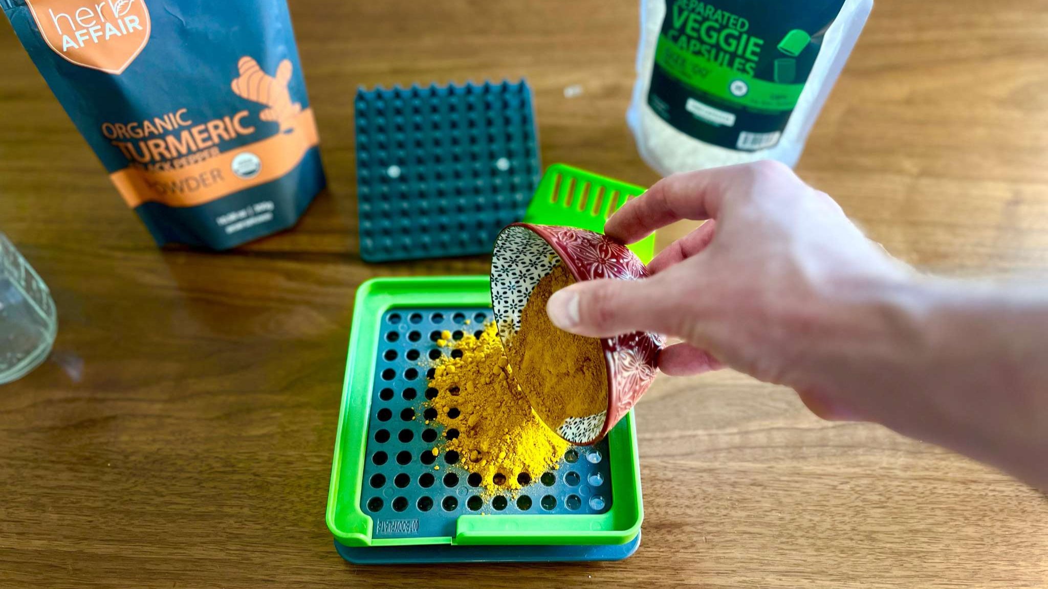 Pouring turmeric powder into capsule-it tray