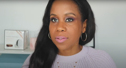 A woman sat in a well-lit room about to put on her makeup