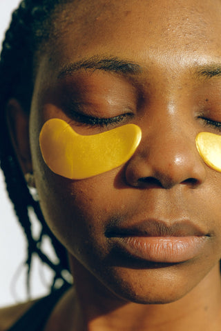 A woman with her eyes closed while using under eye masks to hydrate her skin